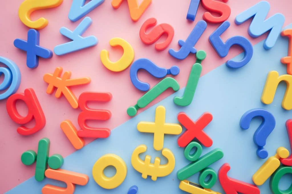 Colorful numbers and letters are displayed scattered around on a pink and blue background.
