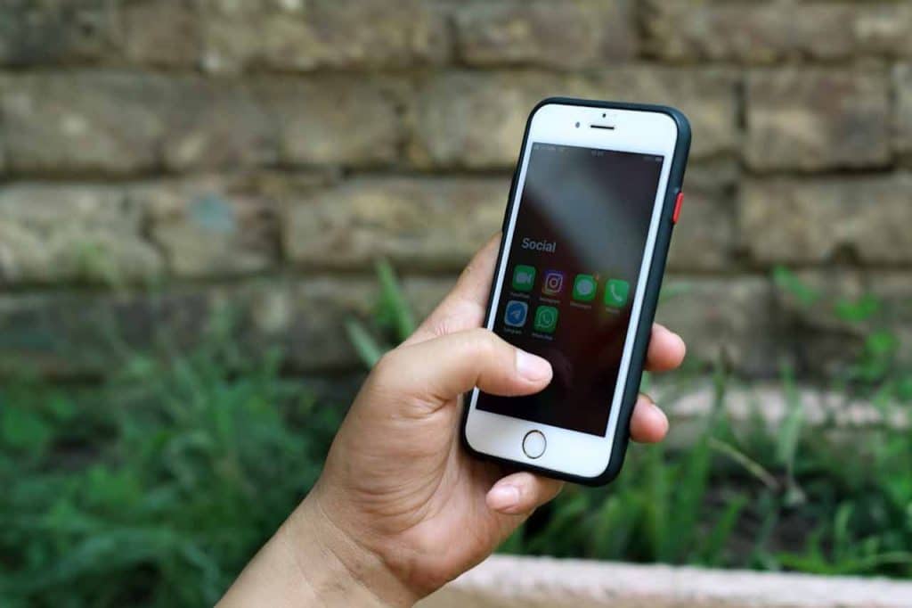 A landscaping business owner is looking at their cellphone. The cellphone is displaying multiple social media apps.