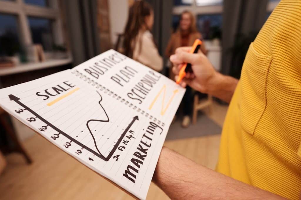 A person holding a notepad that displays a schedule for their landscaping company's marketing business plan.