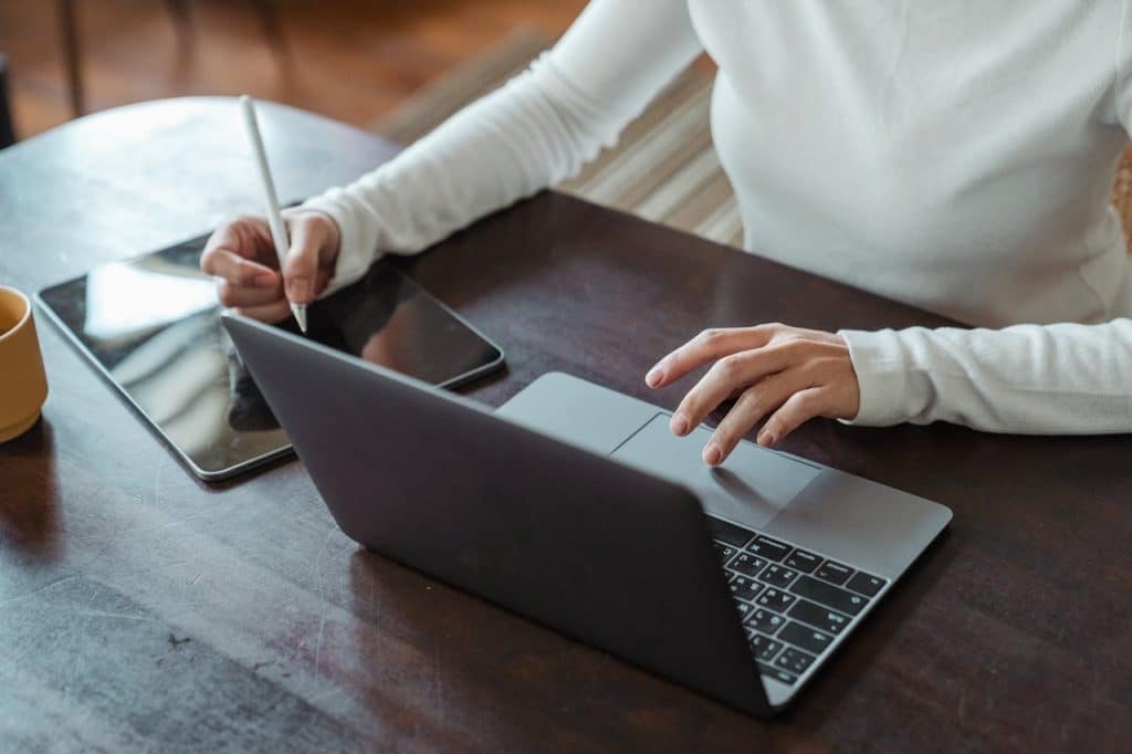 A landscaping business owner planning out their work schedule on a laptop and tablet.
