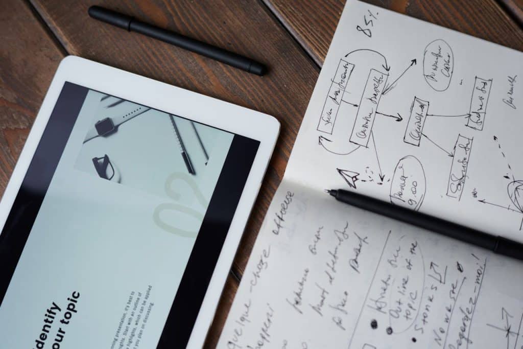 An open notepad with writing and a tablet with a presentation displaying information about landscaping.