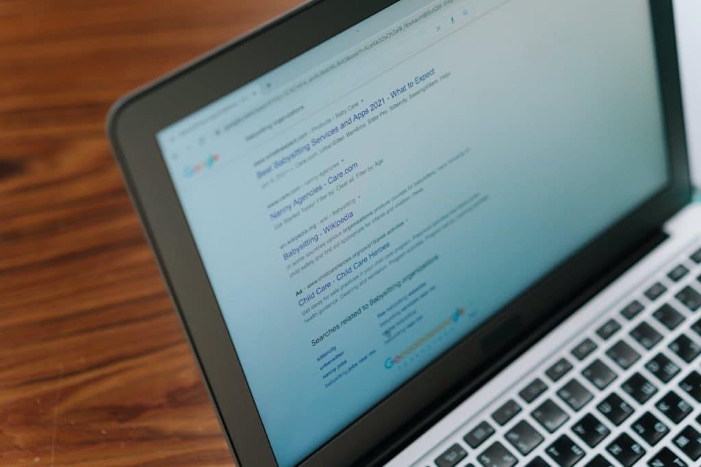 An open laptop, displaying Google search results for lawn care and landscaping companies.