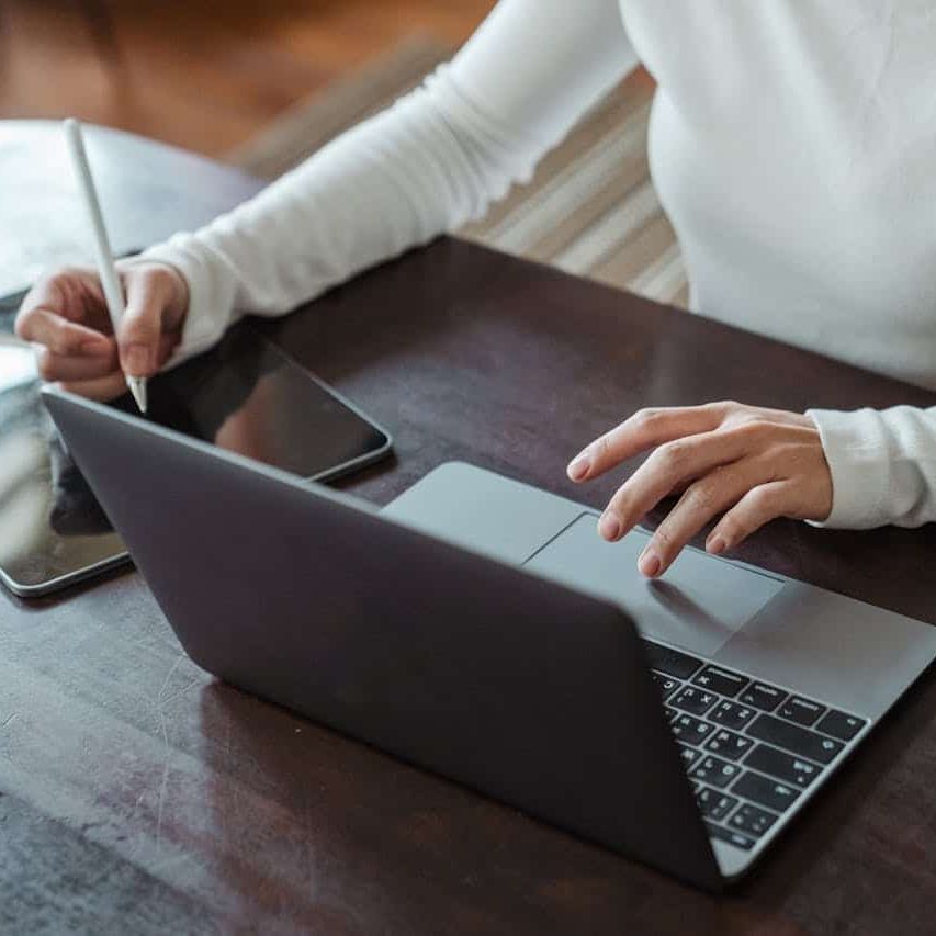 A landscaping business owner planning out their work schedule on a laptop and tablet.